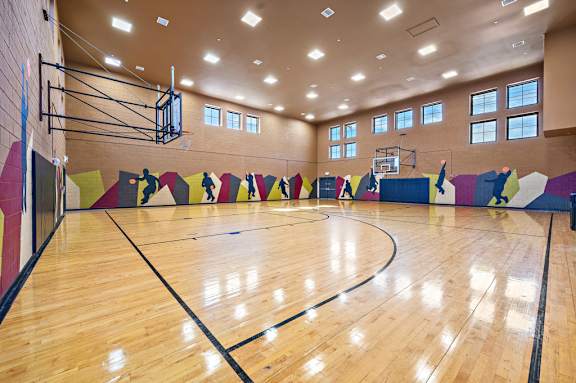 A basketball court with a wooden floor and a basketball hoop.