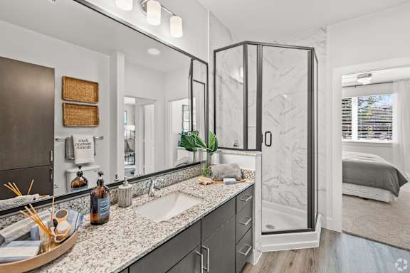 A bathroom with a sink, mirror, and shower.