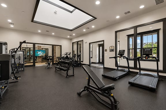 A spacious gym with a variety of equipment including treadmills, benches, and weights.