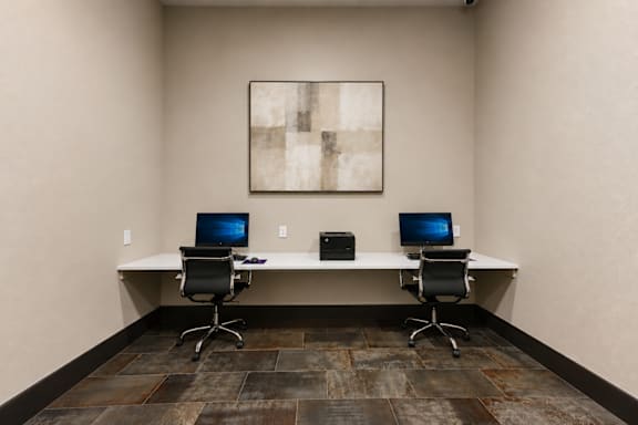 A room with a desk, two chairs and a laptop.