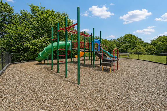 A playground with a green slide and red and green play structures.