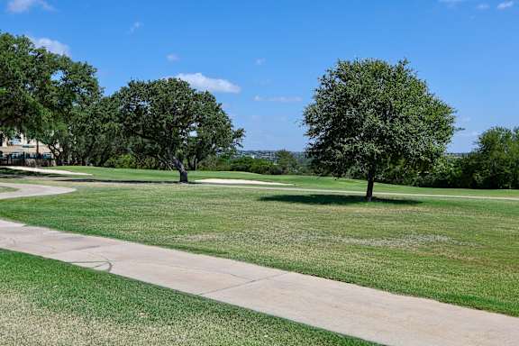Outdoor a park with green grass and trees and a sidewalk
