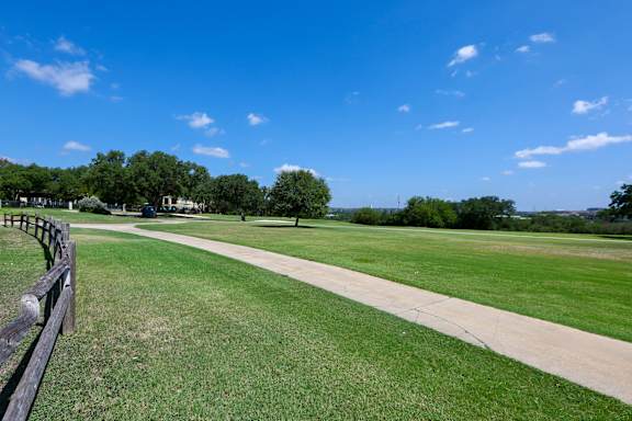 a walking path through a park with grass and trees at TalaVera Apartments, Texas