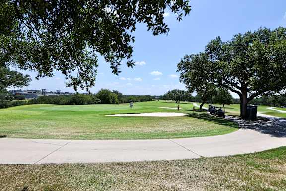 a golf course in a park with trees and a sidewalk at TalaVera Apartments, San Antonio