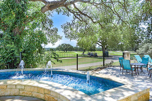 a swimming pool with water fountains and a table and chairs at TalaVera Apartments, San Antonio, TX, 78232