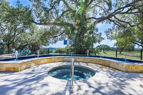 a small pool with a stone wall and a tree at TalaVera Apartments, San Antonio, TX