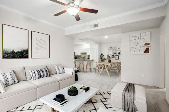 A living room with a white couch, a coffee table, and a ceiling fan.