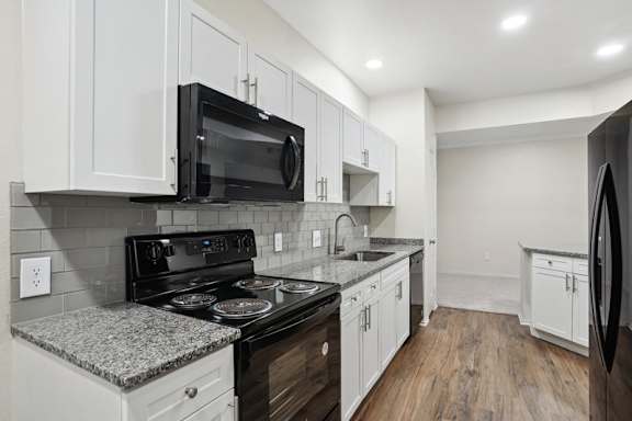 A kitchen with black appliances and white cabinets.
