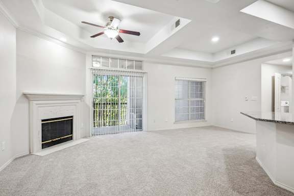 A spacious living room with a fireplace and a ceiling fan.