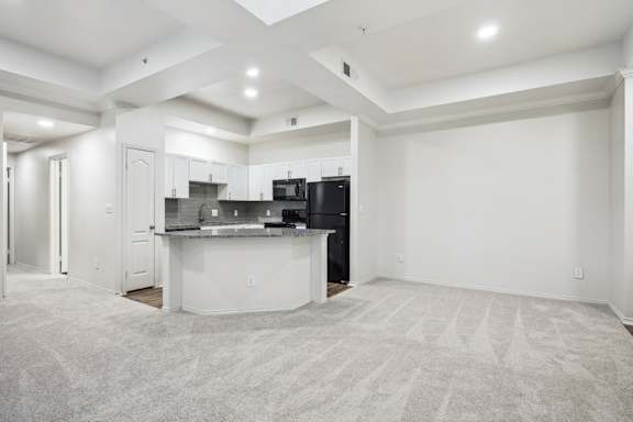 A spacious kitchen with a bar area and a carpeted floor.
