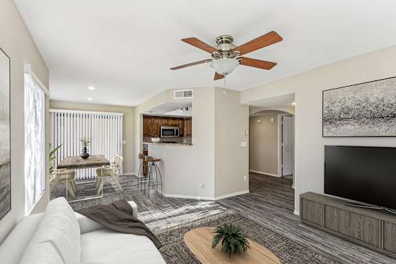 A living room with a white couch and a ceiling fan. at San Montego Apartments, Mesa, AZ