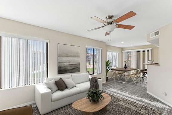 A living room with a white couch, a brown coffee table, and a ceiling fan. at San Montego Apartments, Mesa