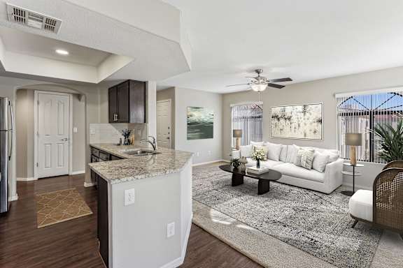 A modern kitchen with a white island and a white sofa in the living room. at San Montego Apartments, Mesa, Arizona