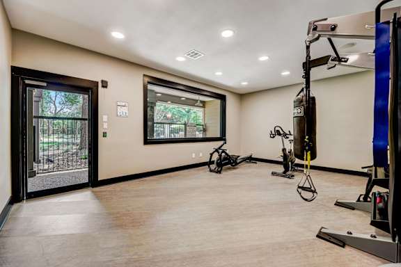 A gym with a variety of exercise equipment including a stationary bike, a rowing machine, and a weight machine. at Ventana Oaks Apartments, Texas, 78717