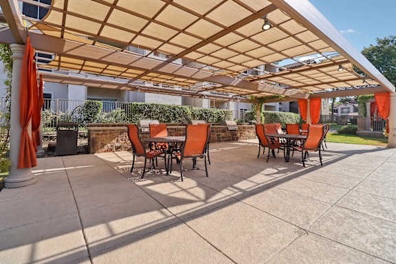 A patio with orange chairs and a wooden pergola.