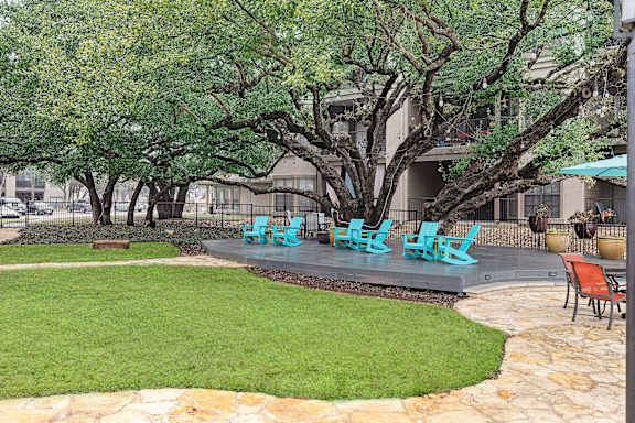 A patio with blue chairs and grass and trees at Waters Edge Apartment Homes, Georgetown, 78626