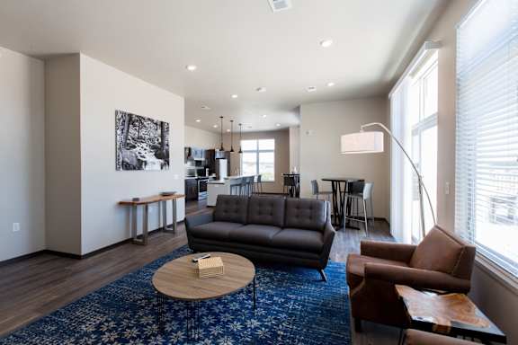 A living room with a black couch and a blue rug.