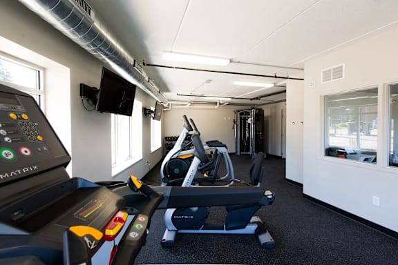 A gym with treadmills and a television.