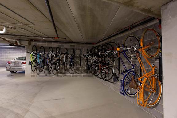 A car is parked in a garage with a wall of bicycles.