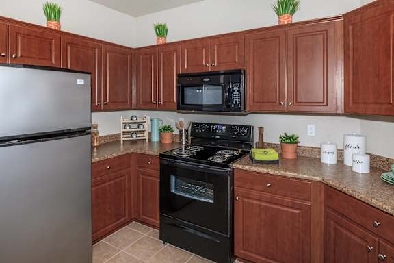 Kitchen with black appliances and brown cabinets at The Presidio by Picerne, N Las Vegas, NV, Nevada
