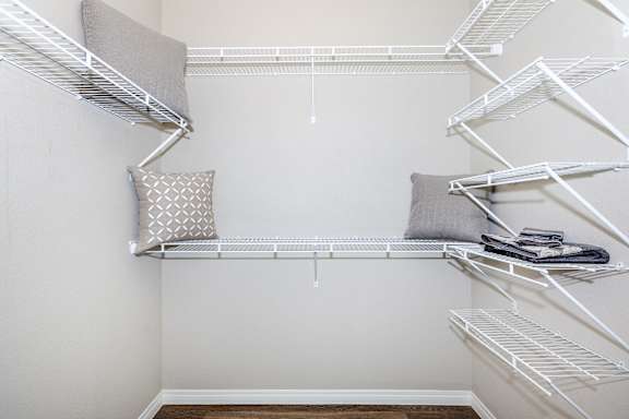 an empty closet with white shelves and a pillow on a shelf