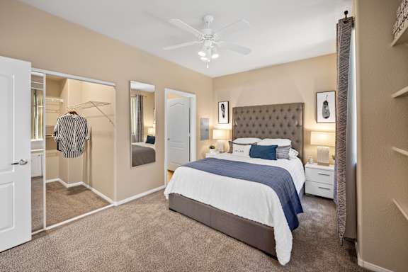 A bedroom with a large bed and a ceiling fan.