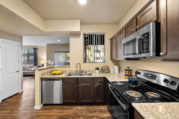 A modern kitchen with dark wood cabinets and stainless steel appliances.
