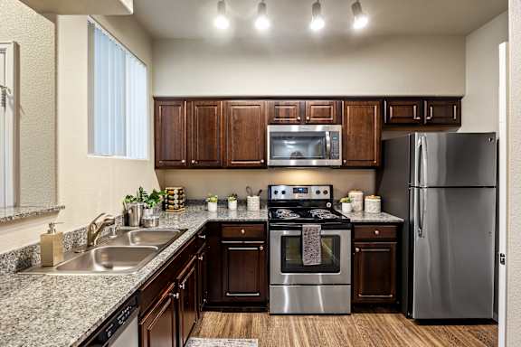 A modern kitchen with dark wood cabinets and stainless steel appliances.