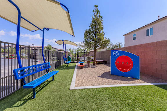 a playground with a blue bench and a playset and umbrella at The Preserve by Picerne, N Las Vegas, NV, 89086