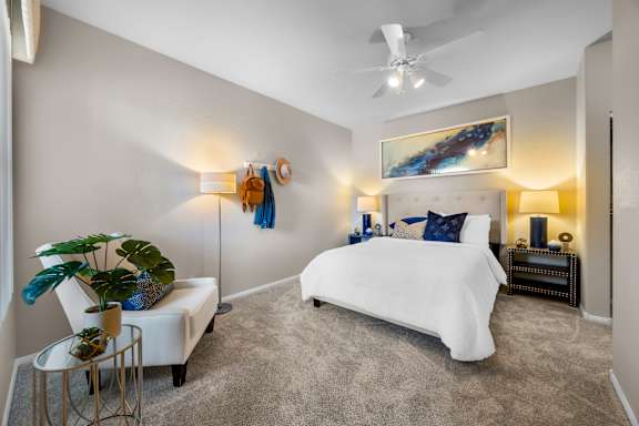 A bedroom with a white bed and a painting on the wall.