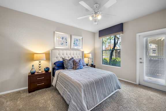 A bedroom with a bed, nightstand, and a ceiling fan.