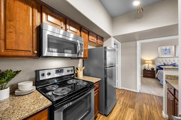 A kitchen with a black stove top oven and a black microwave above it.