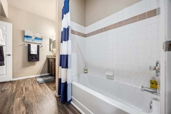 A bathroom with a white tub and a blue and white shower curtain.