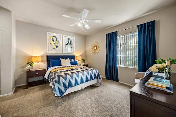 A bedroom with a bed, nightstands, and a ceiling fan.