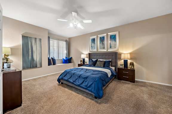 A bedroom with a bed, nightstands, and pictures on the wall.