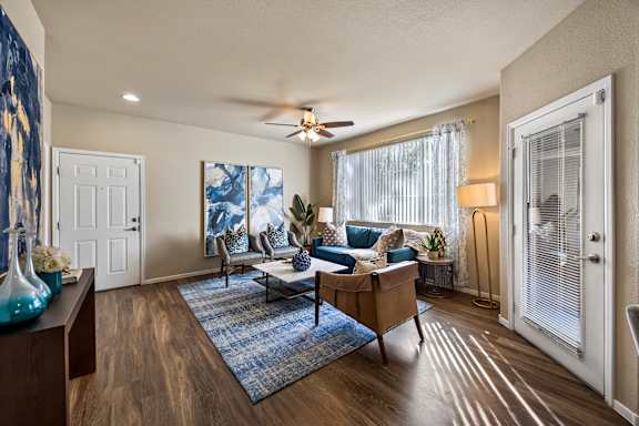 A living room with a blue rug and a wooden floor.