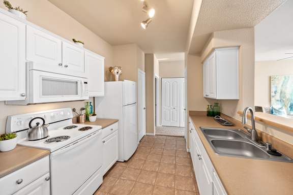A white kitchen with a stove, microwave, and refrigerator.