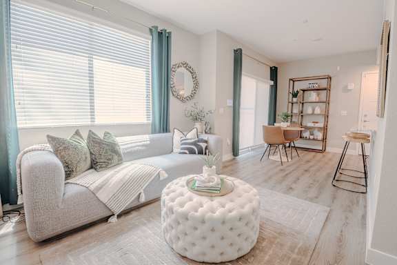 A living room with a white couch and a round ottoman at Level 25 at The Curve by Picerne, Las Vegas, NV, Nevada , 89148