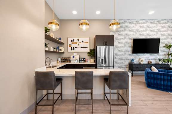 A modern kitchen with a white countertop and grey chairs.
