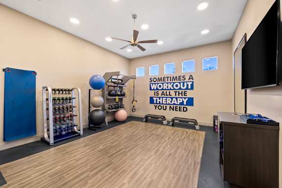 A gym room with a variety of equipment and a motivational quote on the wall.