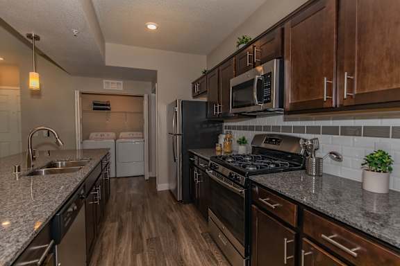 redesigned kitchen with granite countertops and stainless steel appliances and wooden cabinets at Level 25 at Cactus by Picerne Apartments, Las Vegas, Nevada