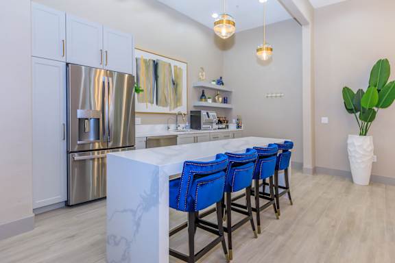 a kitchen with a long island with blue chairs and a stainless steel refrigerator at The Paramount by Picerne, Las Vegas, NV