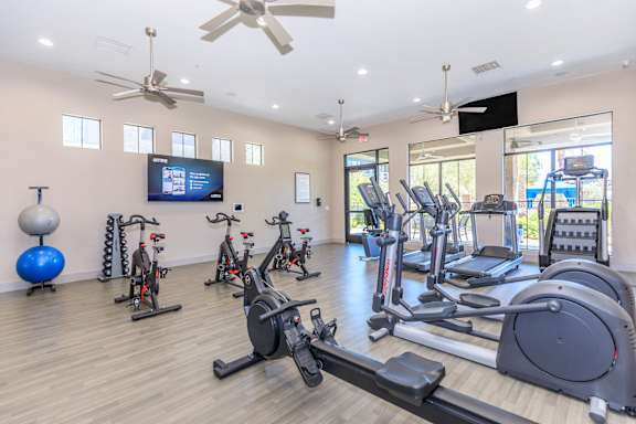 a gym with cardio machines and weights and a tv at The Paramount by Picerne, Las Vegas, 89123