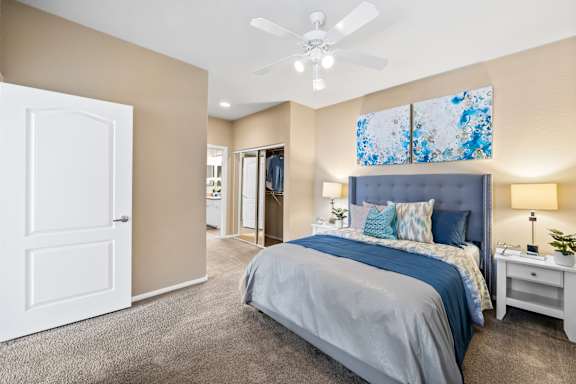 A bedroom with a bed, nightstand, and ceiling fan.
