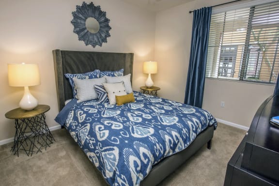 a bedroom with a bed with blue and white bedding and a window at Loreto & Palacio Apartments, Las Vegas, NV