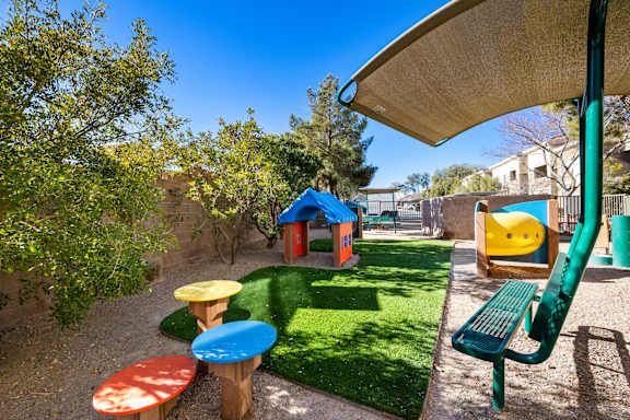 A playground with a green bench and a yellow ball.