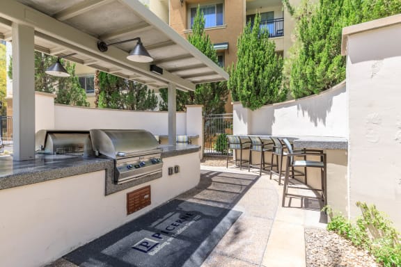 A patio with a grill and chairs under a roof at Loreto & Palacio Apartments, Las Vegas, Nevada