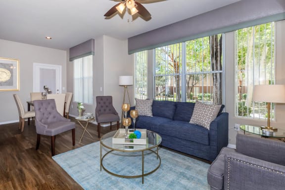a living room with a blue couch and a glass coffee table at The Summit by Picerne, Henderson, NV, 89052