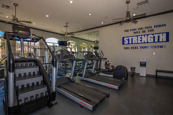 a gym with cardio equipment and a wall with the quote the pain will heal today at The Belmont by Picerne, Las Vegas, NV 89183
