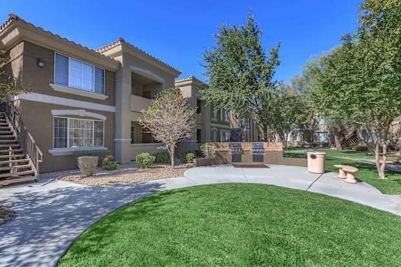 a round lawn in front of a building with trees at The Belmont by Picerne, Las Vegas, 89183